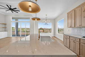 Kitchen featuring open shelves, light stone countertops, backsplash, light wood-style flooring, and hanging light fixtures