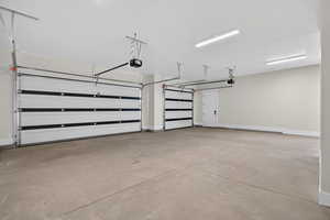 Garage featuring baseboards and a garage door opener