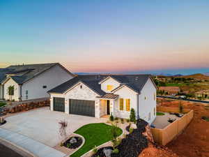 Modern inspired farmhouse with a garage, stone siding, concrete driveway, board and batten siding, and a standing seam roof