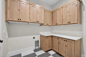 Laundry room with tile patterned floors, electric dryer hookup, and cabinet space