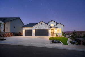 View of front facade with a garage, stone siding, driveway, and a front yard
