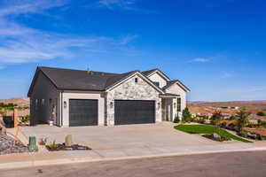 Modern farmhouse featuring an attached garage, concrete driveway, stone siding, and a mountain view