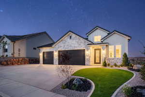 Modern farmhouse style home with a lawn, an attached garage, stone siding, and concrete driveway