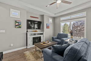 Living room featuring plenty of natural light, wood finished floors, a glass covered fireplace, and ceiling fan