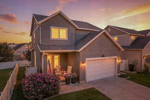 Traditional home with covered porch, stucco siding, concrete driveway, a garage, and roof with shingles