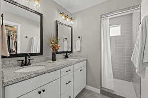 Bathroom with double vanity, a stall shower, a spacious closet, and light tile patterned floors