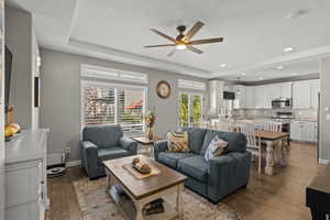 Living room with a raised ceiling, dark wood-style flooring, a textured ceiling, recessed lighting, and a ceiling fan