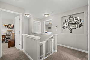 Hallway with an upstairs landing, carpet floors, and a textured ceiling