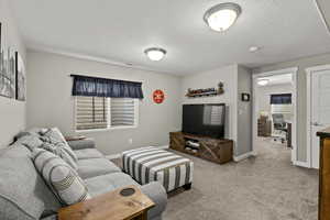 Living area featuring light carpet, a textured ceiling, and an office area