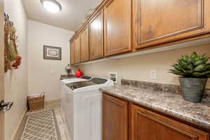 Laundry room featuring cabinet space, light tile patterned floors, and washer and dryer