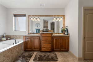Full bathroom with double vanity, a whirlpool tub, and light tile patterned floors