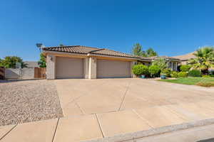 View of front of property with stucco siding, a gate, a tiled roof, an attached garage, and concrete driveway