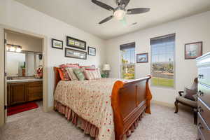 Bedroom with light colored carpet, a ceiling fan, and ensuite bath