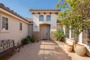 Entrance to property featuring stucco siding, stone siding, and a tile roof