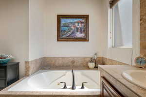 Full bathroom featuring vanity, plenty of natural light, and a tub with jets