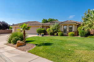 Mediterranean / spanish house with stucco siding, a front lawn, an attached garage, driveway, and stone siding