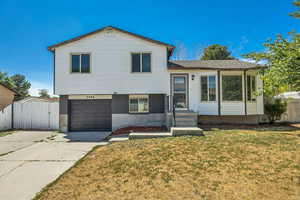 Split level home with brick siding, a garage, and concrete driveway