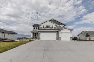 Craftsman house with stone siding, a garage, concrete driveway, and a mountain view