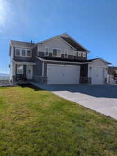 View of front facade with stone siding, a front yard, and board and batten siding