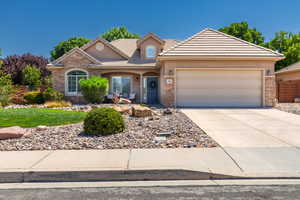 View of front of home with stone siding, a tiled roof, and driveway