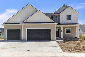 Modern farmhouse with board and batten siding, concrete driveway, covered porch, and a garage