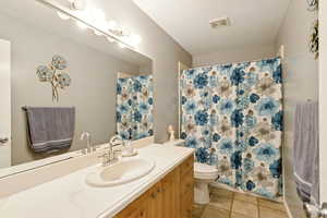 Full bathroom featuring vanity, light tile patterned floors, and curtained shower
