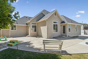 Rear view of property featuring a shingled roof, a patio area, stucco siding, and entry steps
