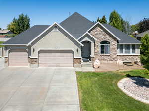 Craftsman-style home with stone siding, a front yard, and a shingled roof