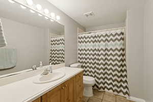 Bathroom with light tile patterned flooring, vanity, a shower with shower curtain, and a textured ceiling