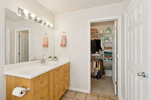 Bathroom featuring vanity, light tile patterned floors, and a spacious closet