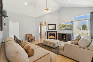 Living room with light tile patterned floors, high vaulted ceiling, a tiled fireplace, ceiling fan, and recessed lighting