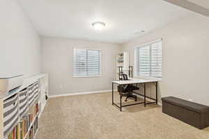 Home office featuring light colored carpet, healthy amount of natural light, and a textured ceiling