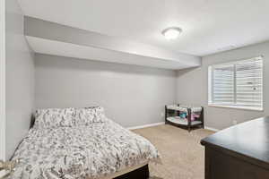 Bedroom featuring light colored carpet and a textured ceiling