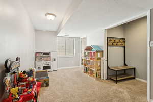 Recreation room with light carpet and a textured ceiling
