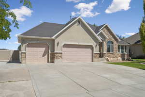 Ranch-style house featuring stone siding, concrete driveway, and stucco siding