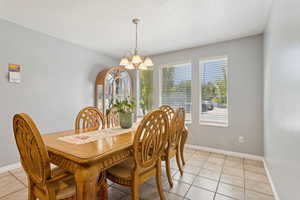 Dining space with light tile patterned flooring and a chandelier