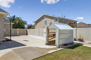 Back of property featuring a gate, a fenced backyard, a storage shed, and stucco siding