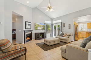 Living room with high vaulted ceiling, light tile patterned flooring, a fireplace, a ceiling fan, and recessed lighting