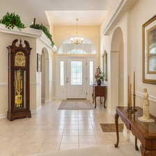Entryway with arched walkways, light tile patterned flooring, and a chandelier