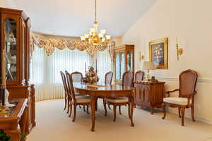 Dining area with light carpet, a chandelier, and lofted ceiling