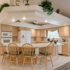 Kitchen with light tile patterned floors, light brown cabinets, light countertops, a kitchen bar, and recessed lighting