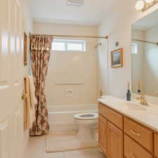 Bathroom featuring shower / bath combo with shower curtain, vanity, and light tile patterned floors