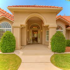 Property entrance with a tile roof, stucco siding, and a lawn