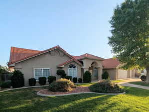 Mediterranean / spanish house featuring a front lawn, stucco siding, a tiled roof, and an attached garage