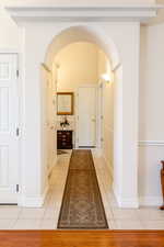 Hallway featuring arched walkways and light tile patterned flooring