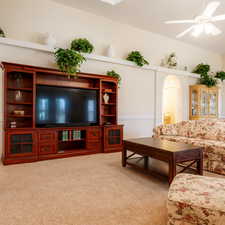Living area featuring light carpet, a ceiling fan, and arched walkways
