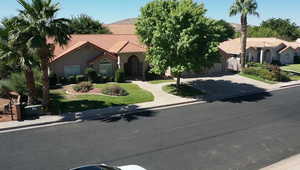 Mediterranean / spanish home featuring a tile roof, driveway, stucco siding, a front lawn, and an attached garage