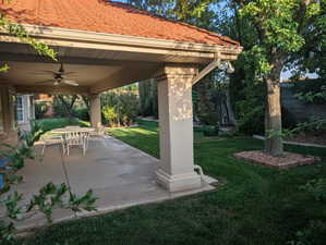 View of green lawn featuring a patio, a ceiling fan, and outdoor dining space