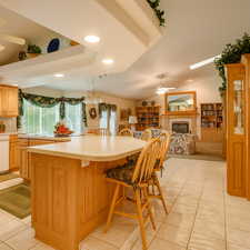 Kitchen featuring ceiling fan, a fireplace, light countertops, lofted ceiling, and a kitchen breakfast bar