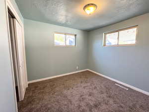 Unfurnished bedroom with a closet, carpet floors, and a textured ceiling